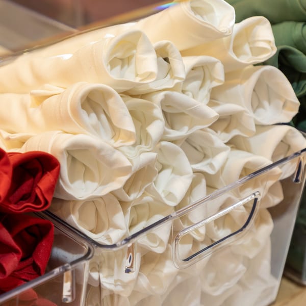 Rolled white, red, and green napkins neatly stored in clear containers, ready for use.