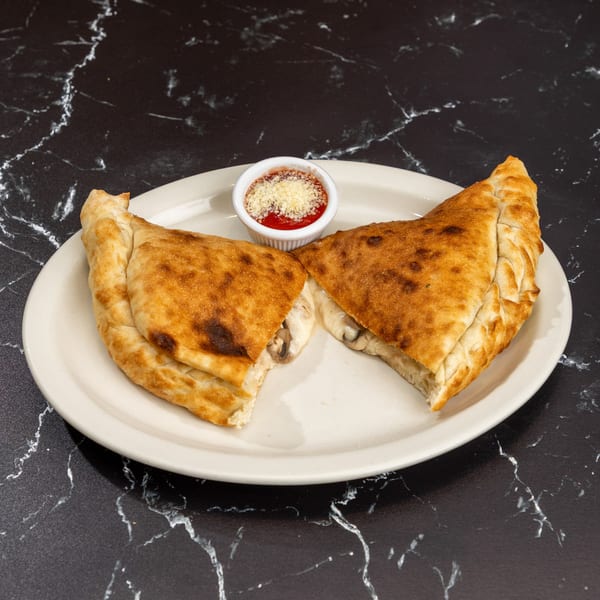 Two golden-brown calzones, cut in half to reveal melted cheese and mushrooms, served with marinara sauce.