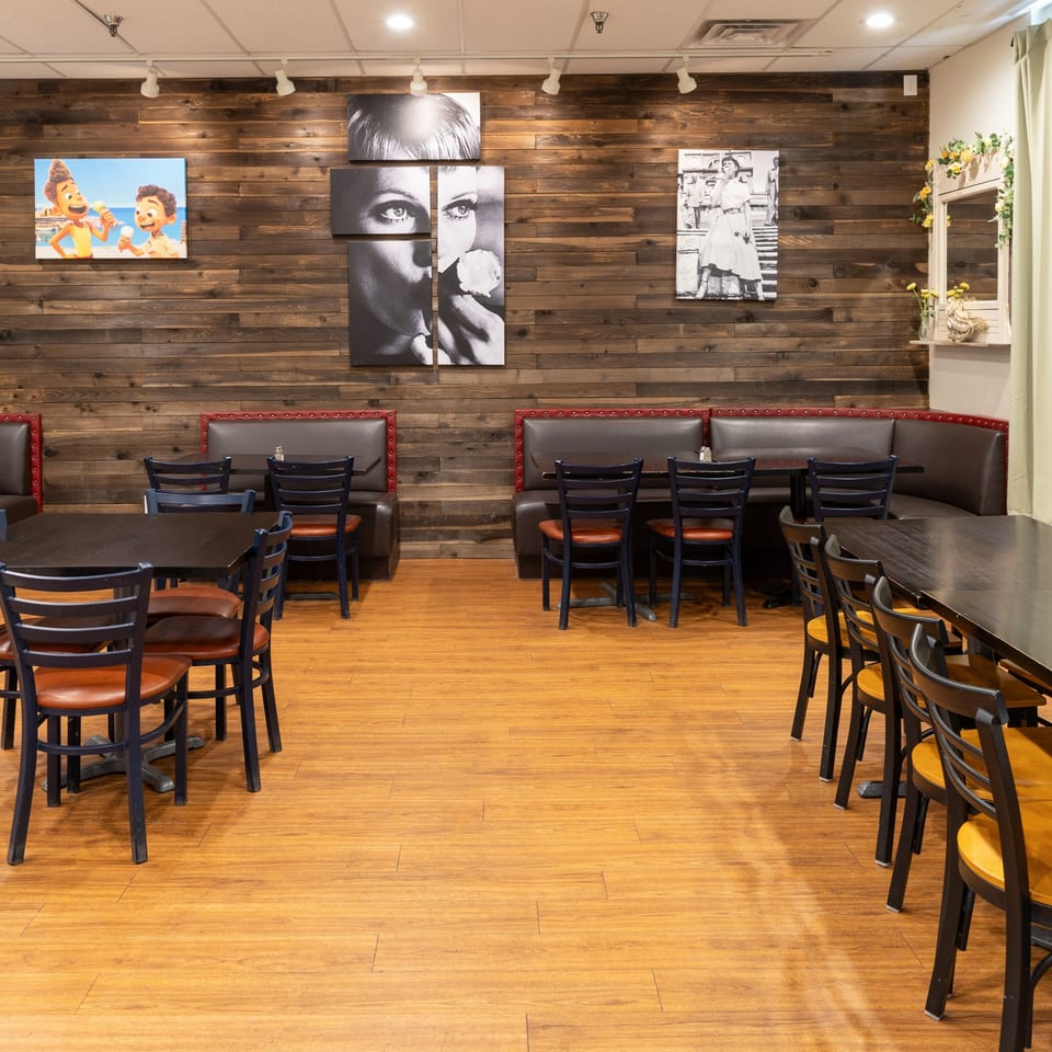 Empty dining room at Ti Amo Wood Fired Pizza with wooden walls, booths, and tables.